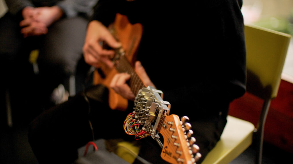 Craig playing the guitar as a demonstration at a 'show and tell event' in the Pervasive Media Studio, Watershed.